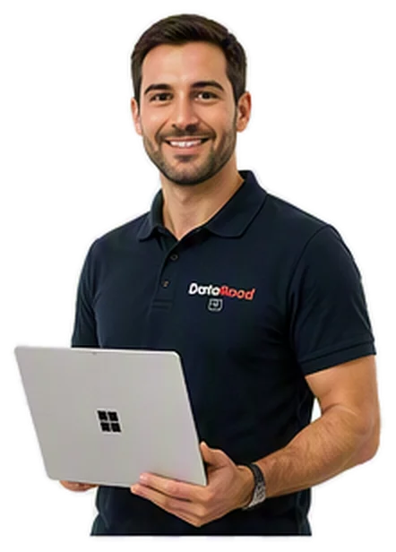 A smiling man in a navy polo shirt, holding a silver laptop, standing in a relaxed pose.
