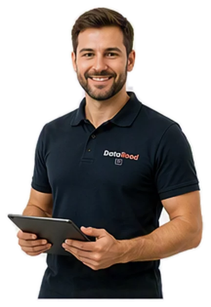 Homme souriant vêtu d'un polo foncé tenant une tablette, suggérant un membre du personnel prêt à aider.